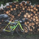 green and black mountain bike beside brown wood logs