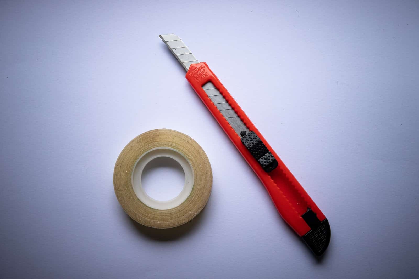red and black click pen beside white tape roll